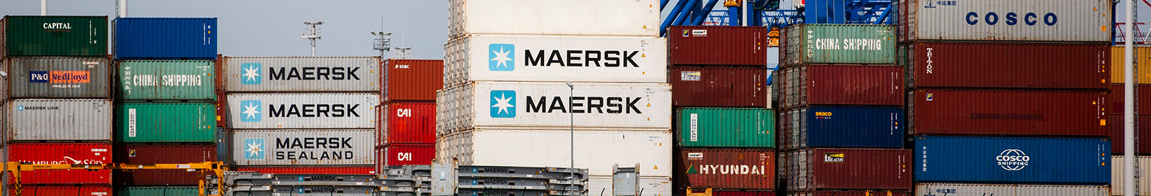 Imagem de um porto com vários contêineres da Maersk, evidenciando o foco na gigante. Os contêineres estão organizados em fileiras, refletindo a operação robusta da empresa e destacando seus planos de expansão e investimentos no Brasil.