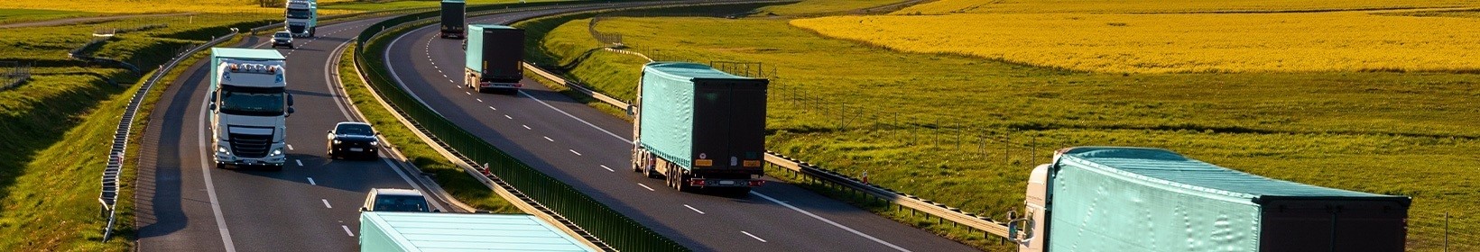 Imagem de caminhões circulando por uma estrada, com uma vista ampla que destaca o tráfego e a movimentação.